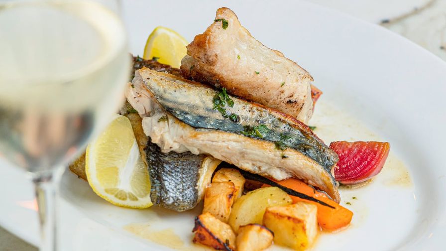 Plato de pescado blanco con limón y verduras asadas.