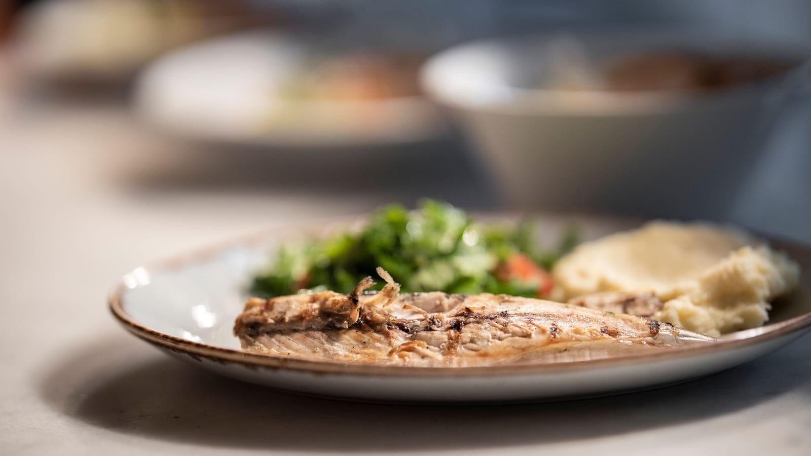 Pescado con patata y judías verdes servido en un plato con presentación sencilla.