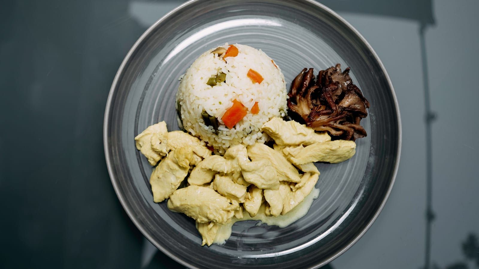 Plato de pollo con arroz, verduras y champiñones servido en cerámica.