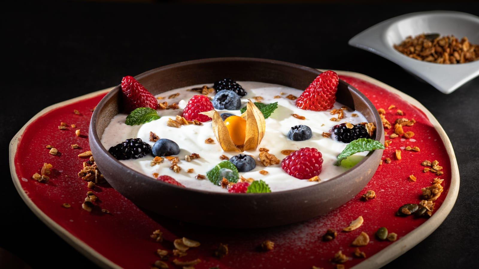 Yogur con frutos rojos y nueces servido en un plato con presentación sencilla.