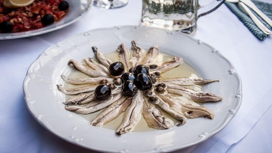 Boquerones servidos con aceitunas y aceite de oliva.