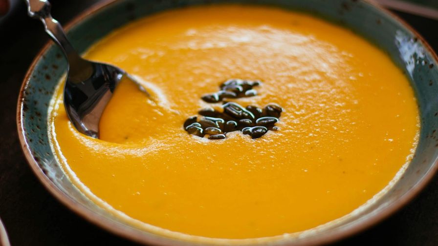 Crema de calabaza con semillas servido en un plato con presentación sencilla.