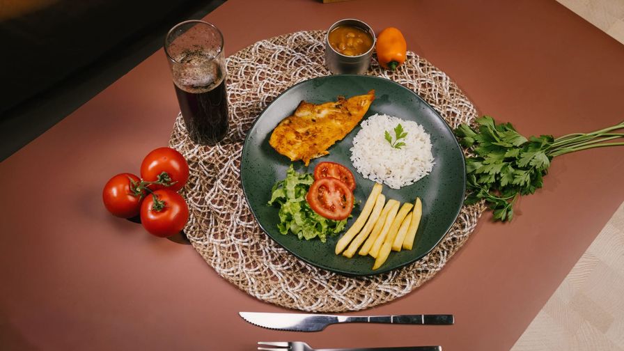 Plato con pescado, arroz y verduras servido en una mesa.